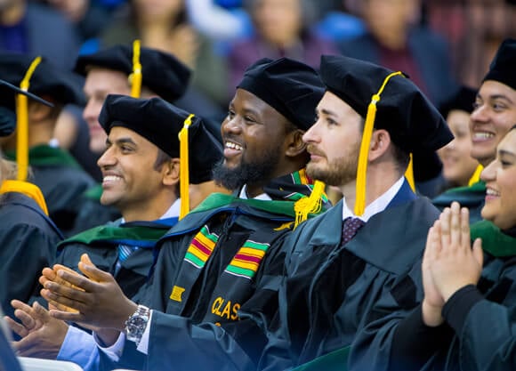 Medical students clap in celebration at their commencement ceremony.