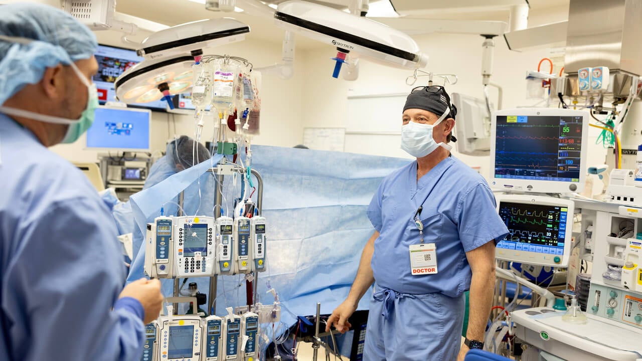 An anesthesiologist in an operating room surrounded by medical equipment.