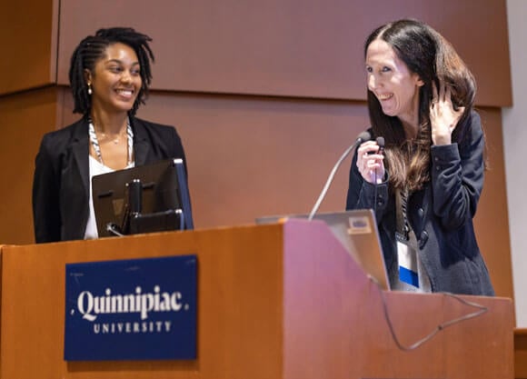 Alumna Holly LaPrade speaks at a podium at the Rare Disease Day Symposium.