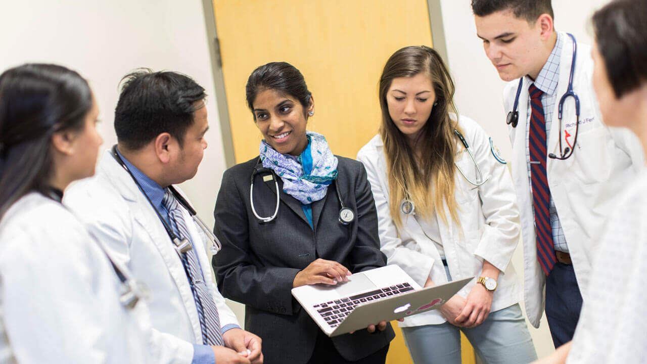 A professor speaks with a handful of medical students in the patient assessment center.