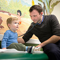 Medical student Brian Wasicek checks the heartbeat of a young patient