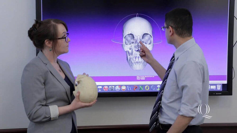 Katelyn Norman speaking in front of a screen with a digital rendition of a skull, starts video