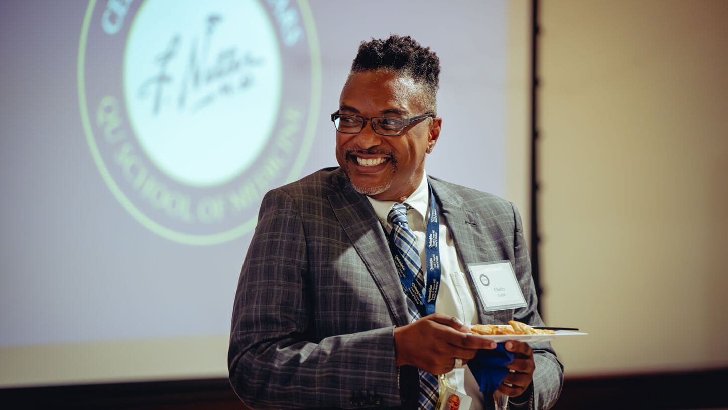 A faculty member smiles at the Symposium